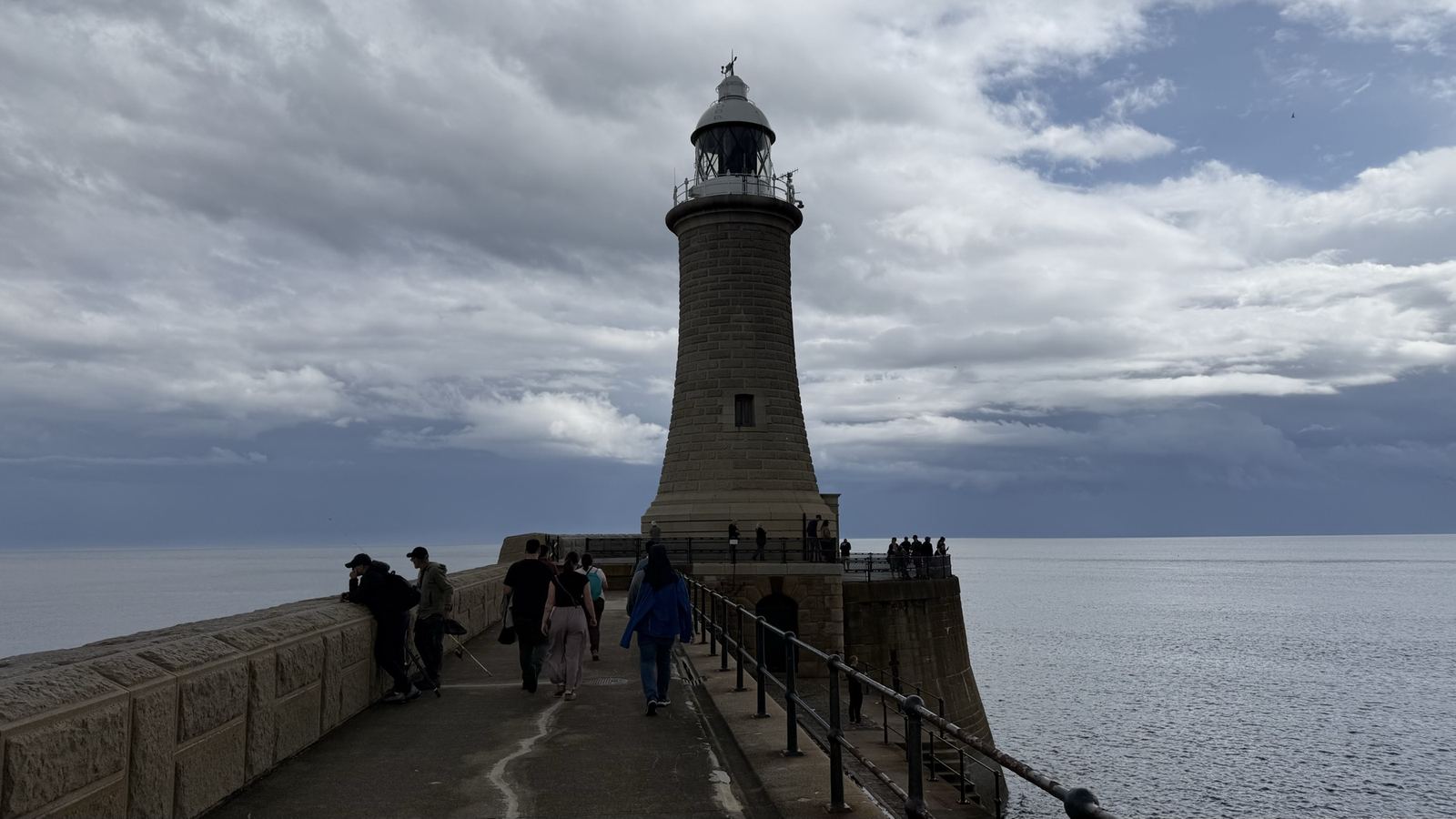 Tynemouth North Pier lighthouse under a dramatic sky, waves on both sides.
